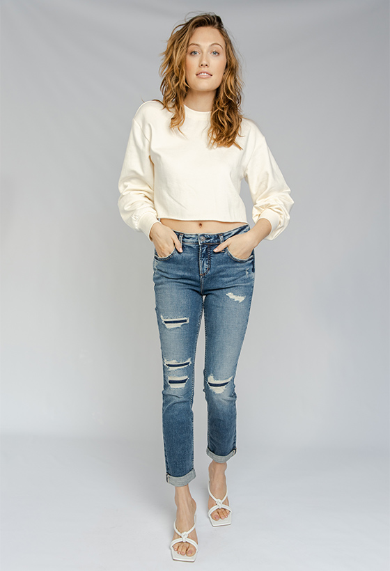 Women’s girlfriend fit slim leg jeans featuring a mid rise and destroyed dark indigo wash